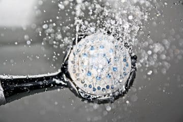 Close-up of a shower head releasing water droplets, creating a crisp and refreshing bathroom scene.