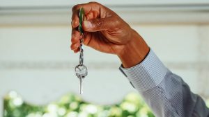 Assurance habitation : comment bien se protéger des dégâts des eaux dans une maison design moderne ? A hand holding a set of house keys, symbolizing buying or renting a new home.