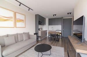 Dans nos intérieurs, la table à manger redevient la vraie pièce centrale Elegant modern living space with grey couch, minimalist decor, and open kitchenette.