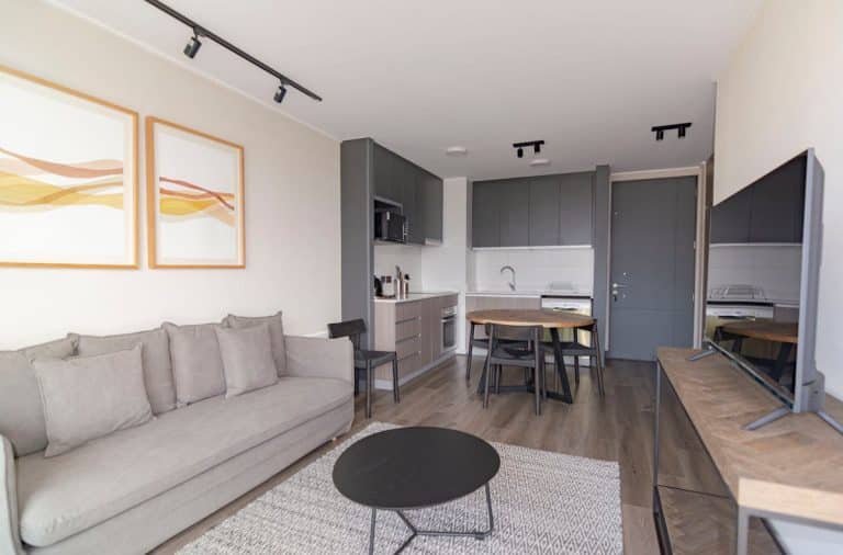 Dans nos intérieurs, la table à manger redevient la vraie pièce centrale Elegant modern living space with grey couch, minimalist decor, and open kitchenette.