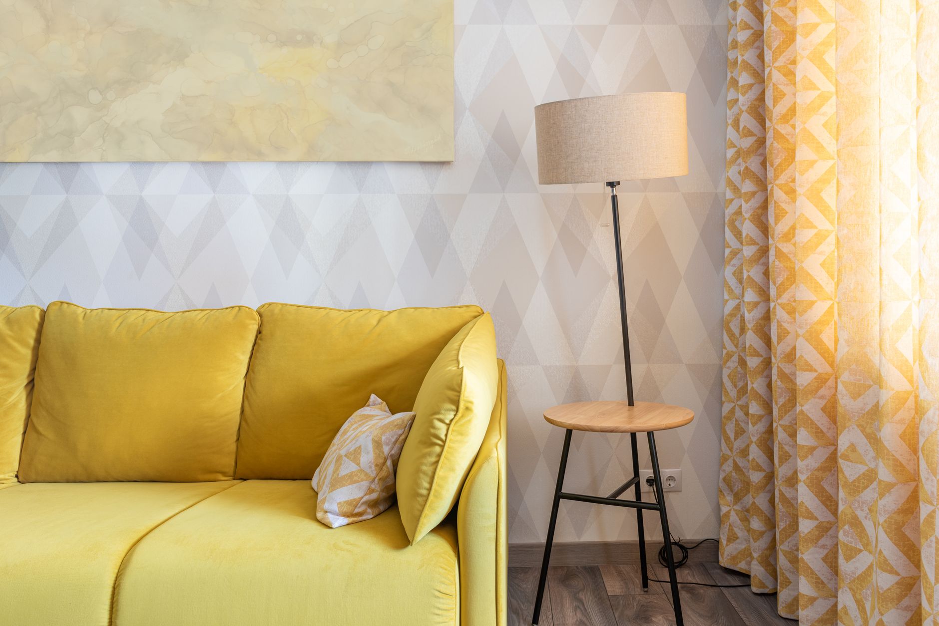 Intérieur de chambre contemporain avec coussins sur le canapé devant une lampe et un rideau avec un ornement à la maison