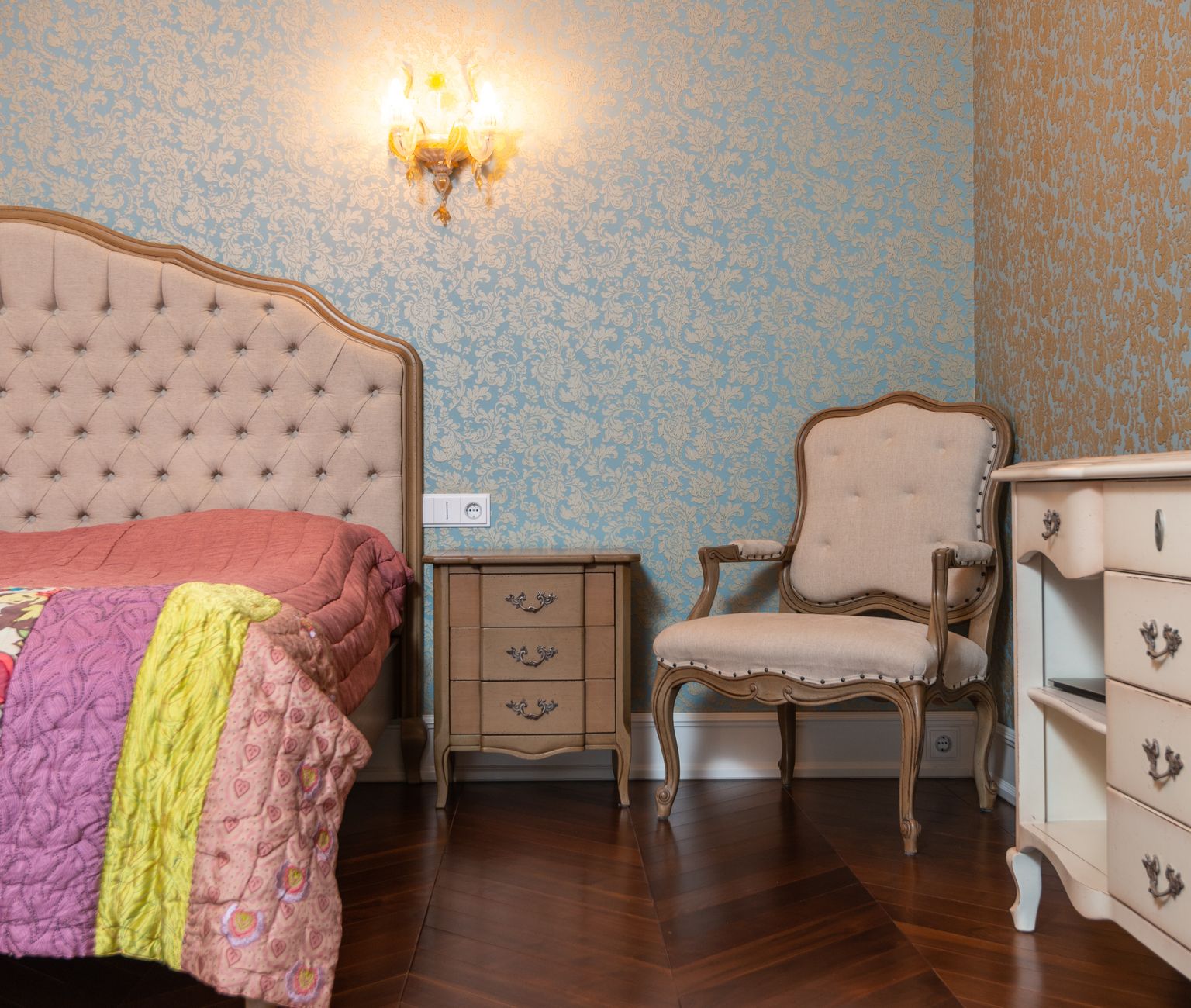 Décor de chambre chic avec meubles vintage, papier peint à motifs et éclairage cosy.