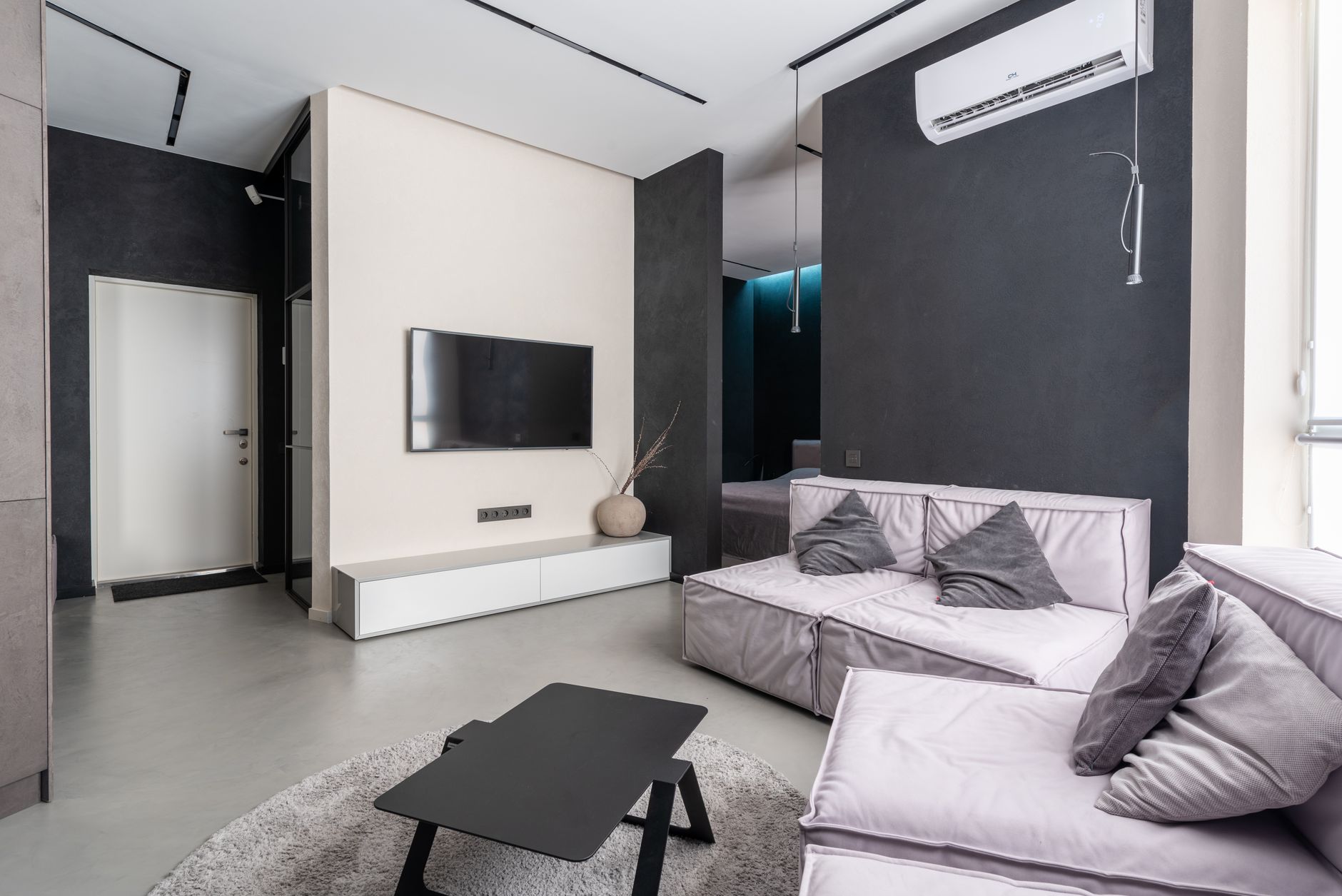 Intérieur d'un salon contemporain spacieux avec des canapés confortables et moelleux avec des coussins et une télévision murale